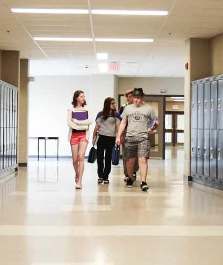 Three students walking down a school hallway