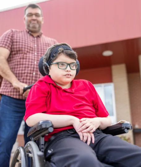 Man pushing a child in a wheelchair.