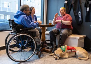 Three people sitting at a cafe with service dog