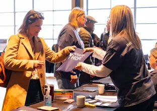 Conference attendee receiving registration materials from a conference volunteer