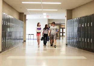 Three students walking down a school hallway