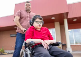 Man pushing a child in a wheelchair. 